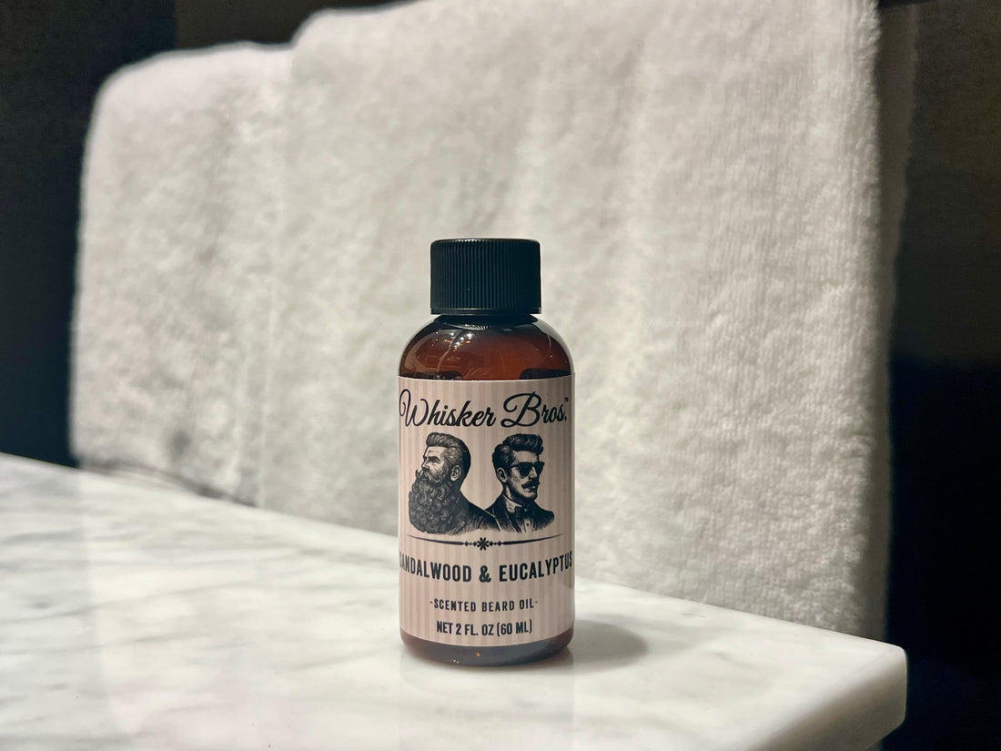 Bottle of Whisker Brand beard oil on a marble surface with a towel in the background