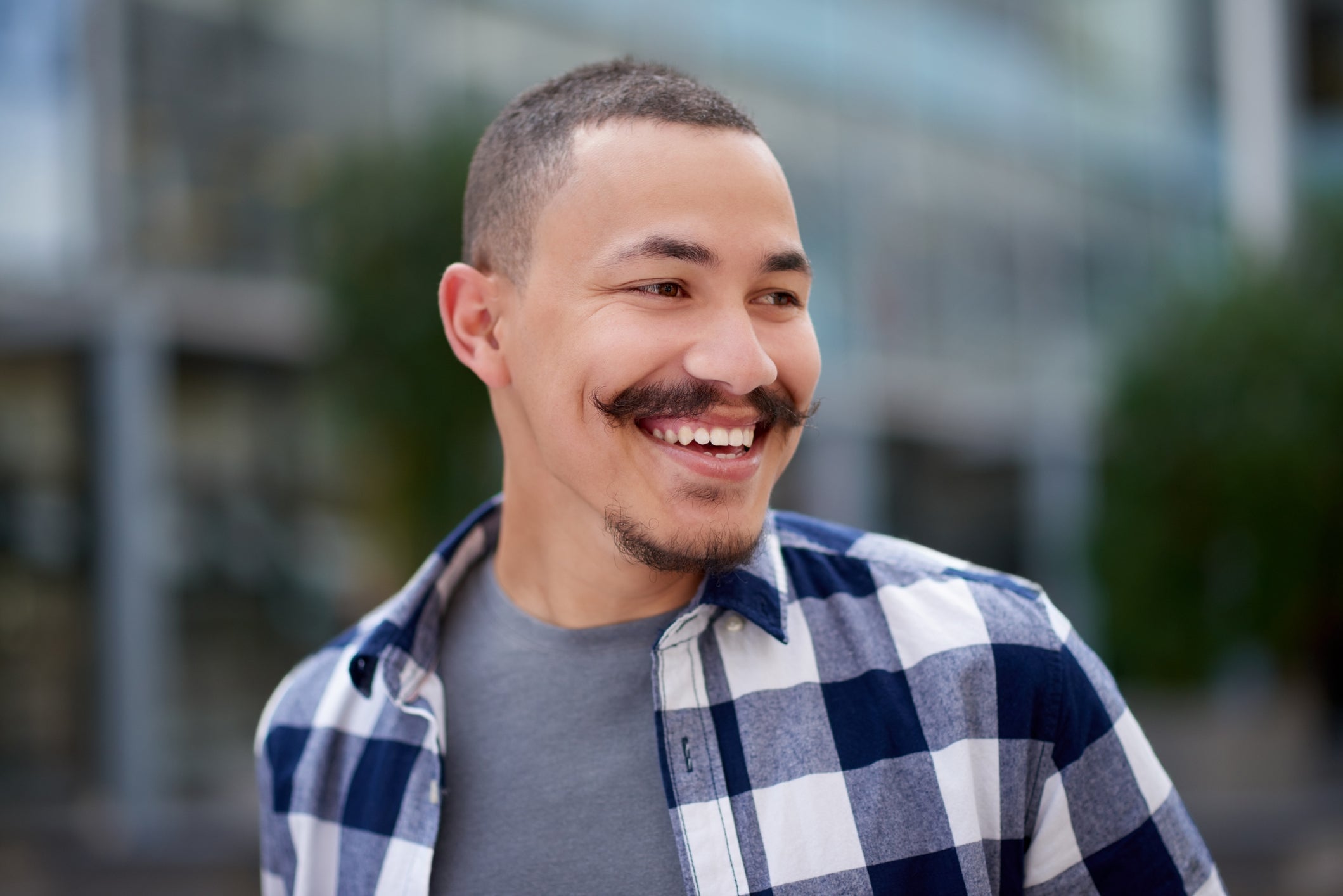 Man wearing a plaid shirt smiling outdoors