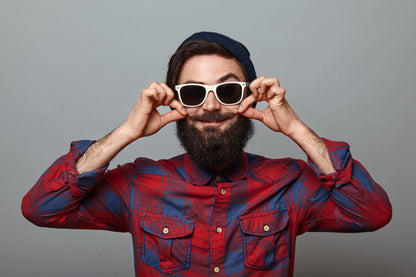 Man wearing a red and blue plaid shirt and sunglasses against a gray background